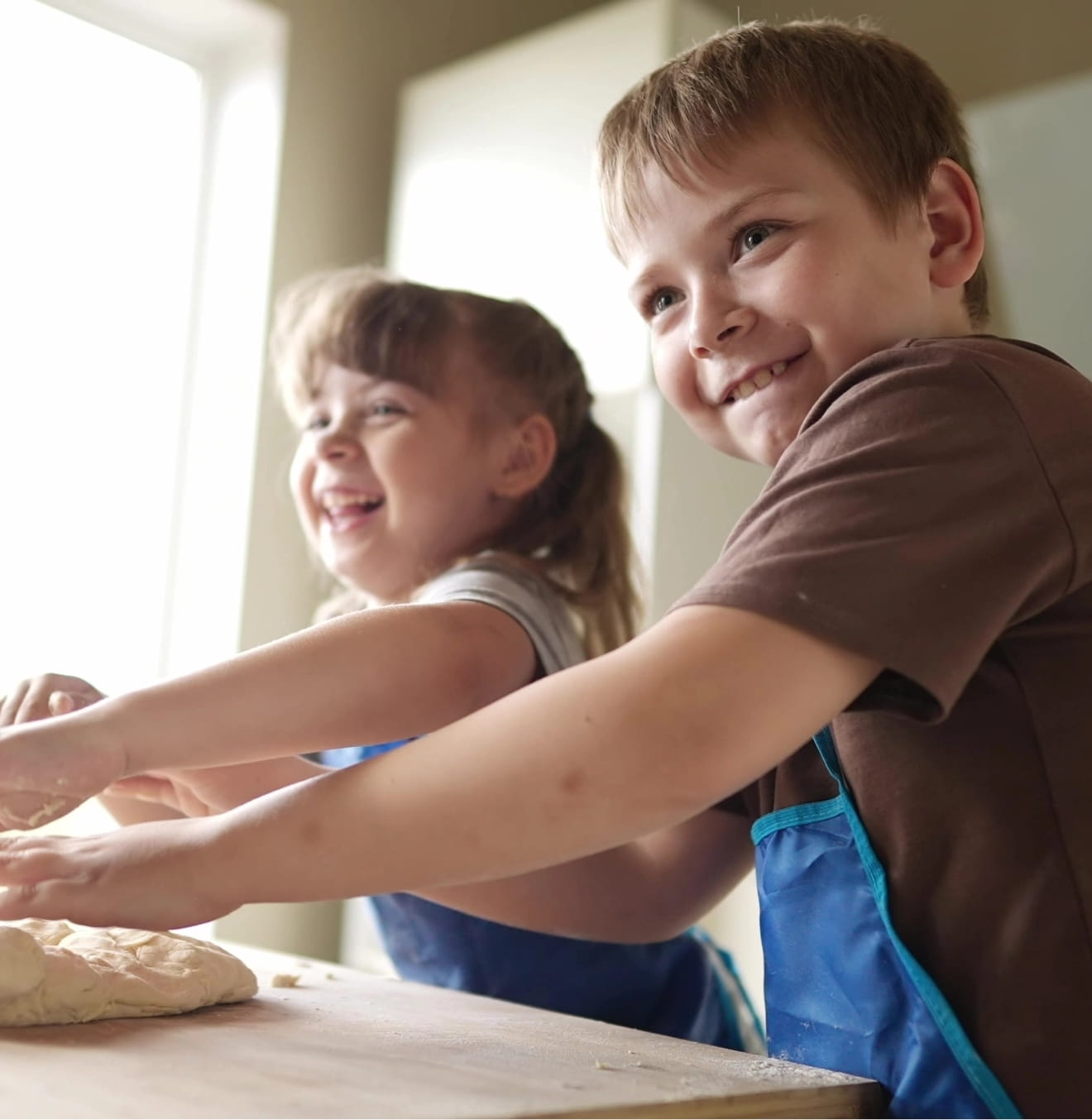 kids kneading dough on a cutting board